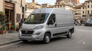 Ten obraz przedstawia nowoczesny, srebrny samochód dostawczy Fiat Ducato zaparkowany na malowniczej, włoskiej ulicy w otoczeniu zabytkowej architektury
